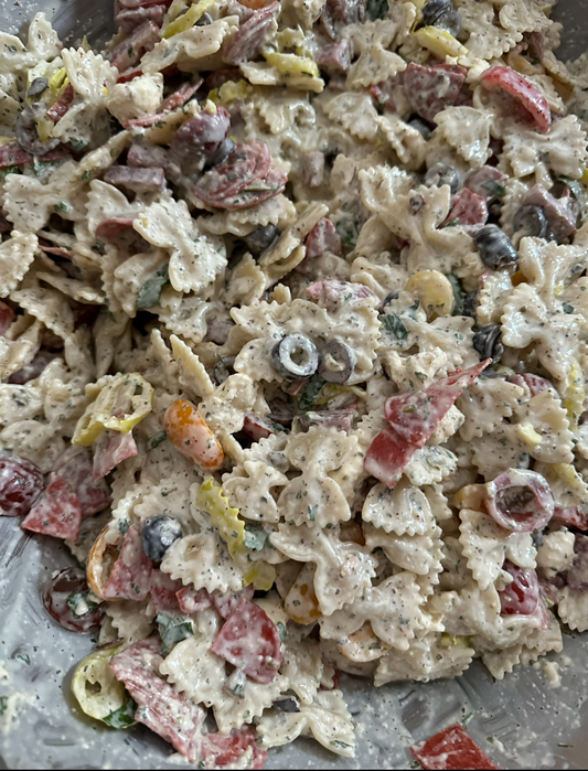 A prepared Italian Pasta Salad with bow tie pasta, salami, pepperoni, black olives, mild banana peppers, heirloom cherry tomato, tossed in our creamy Italian dressing. 
